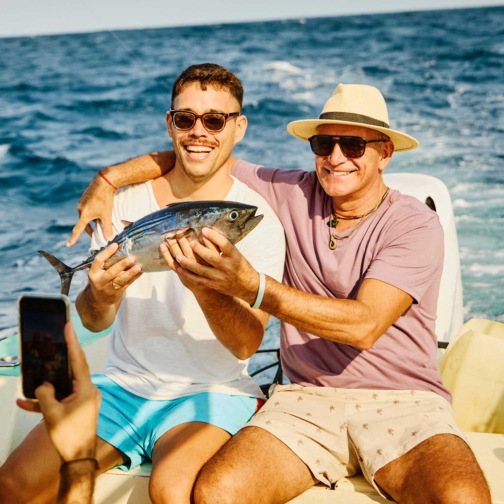 two men on a boat holding a fish