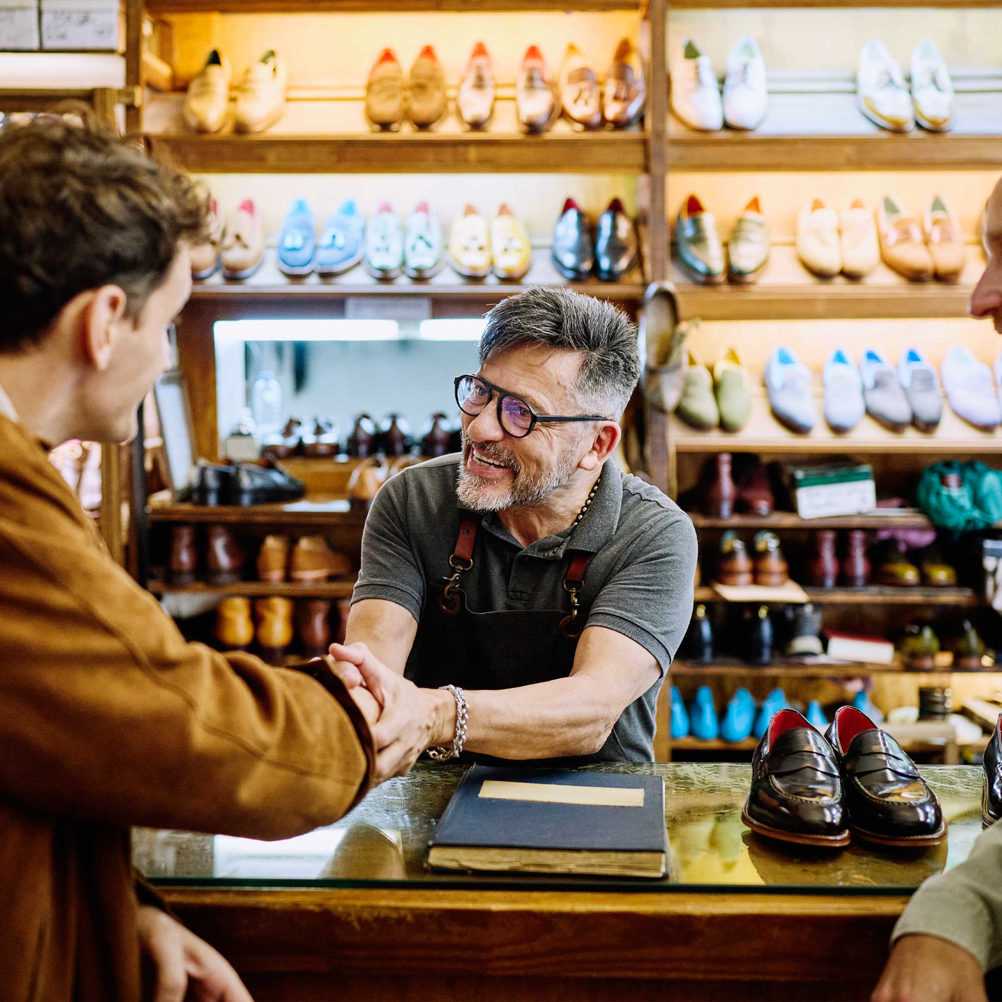a man shaking hands with a couple of people in a shoe store
