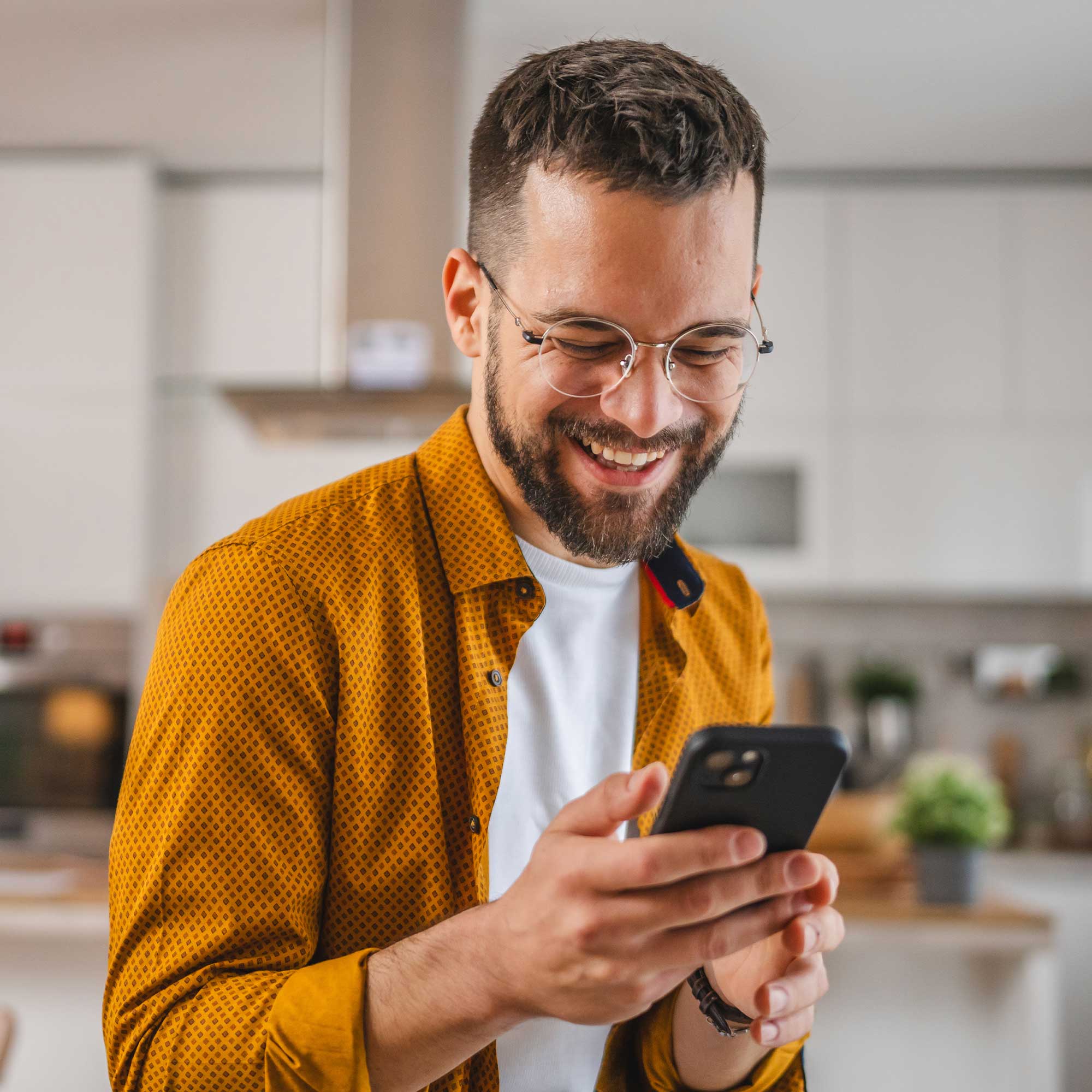 a man smiling while holding a phone