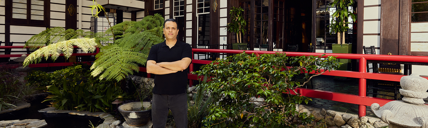 a man standing in front of a building with his arms crossed