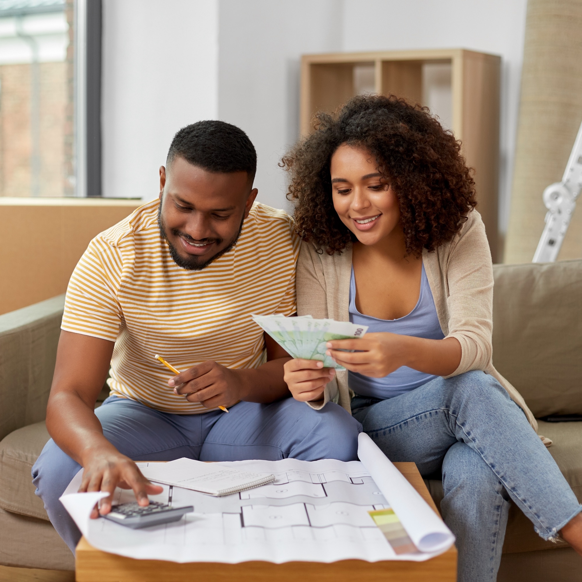 a man and woman sitting on a couch looking at a paper and a calculator