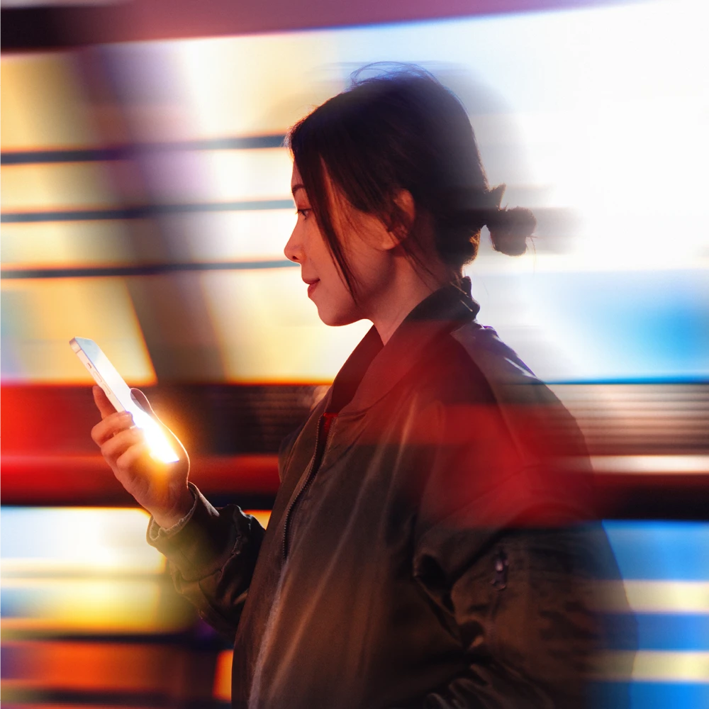 woman using her phone with a moving train behind her woman using her phone with a moving train behind her