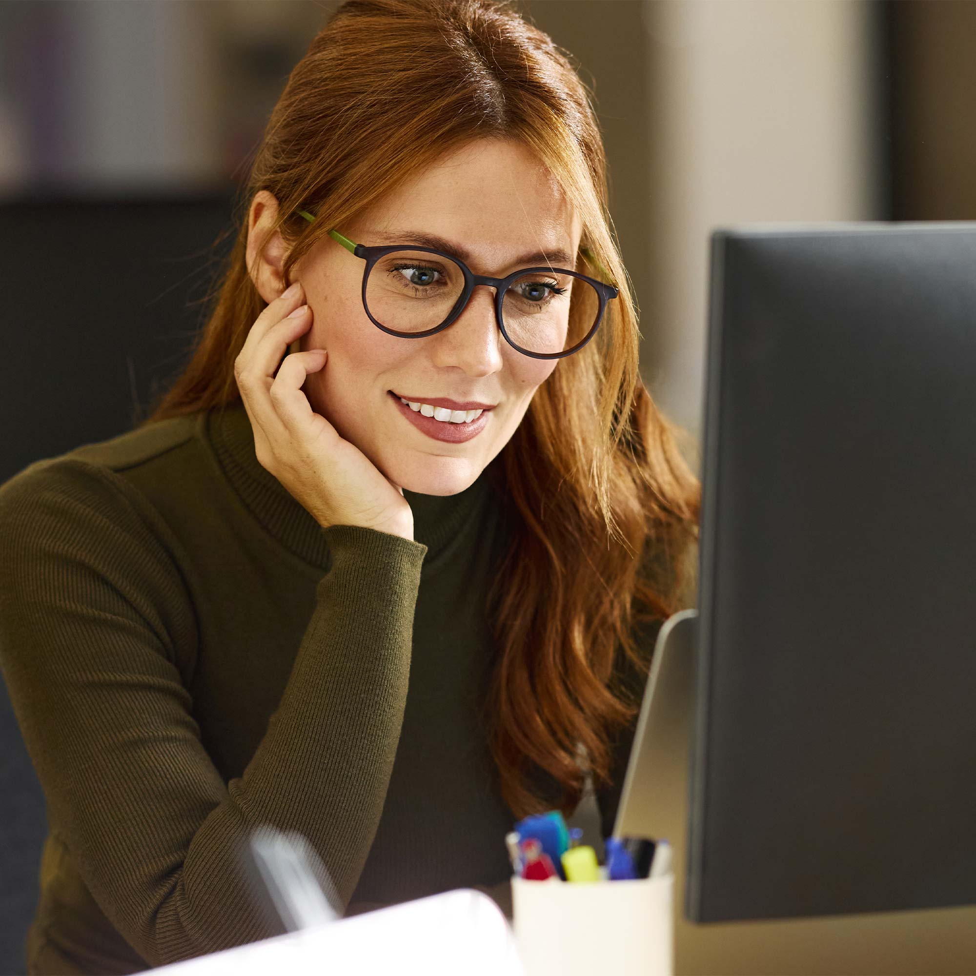 a woman in glasses looking at a computer screen