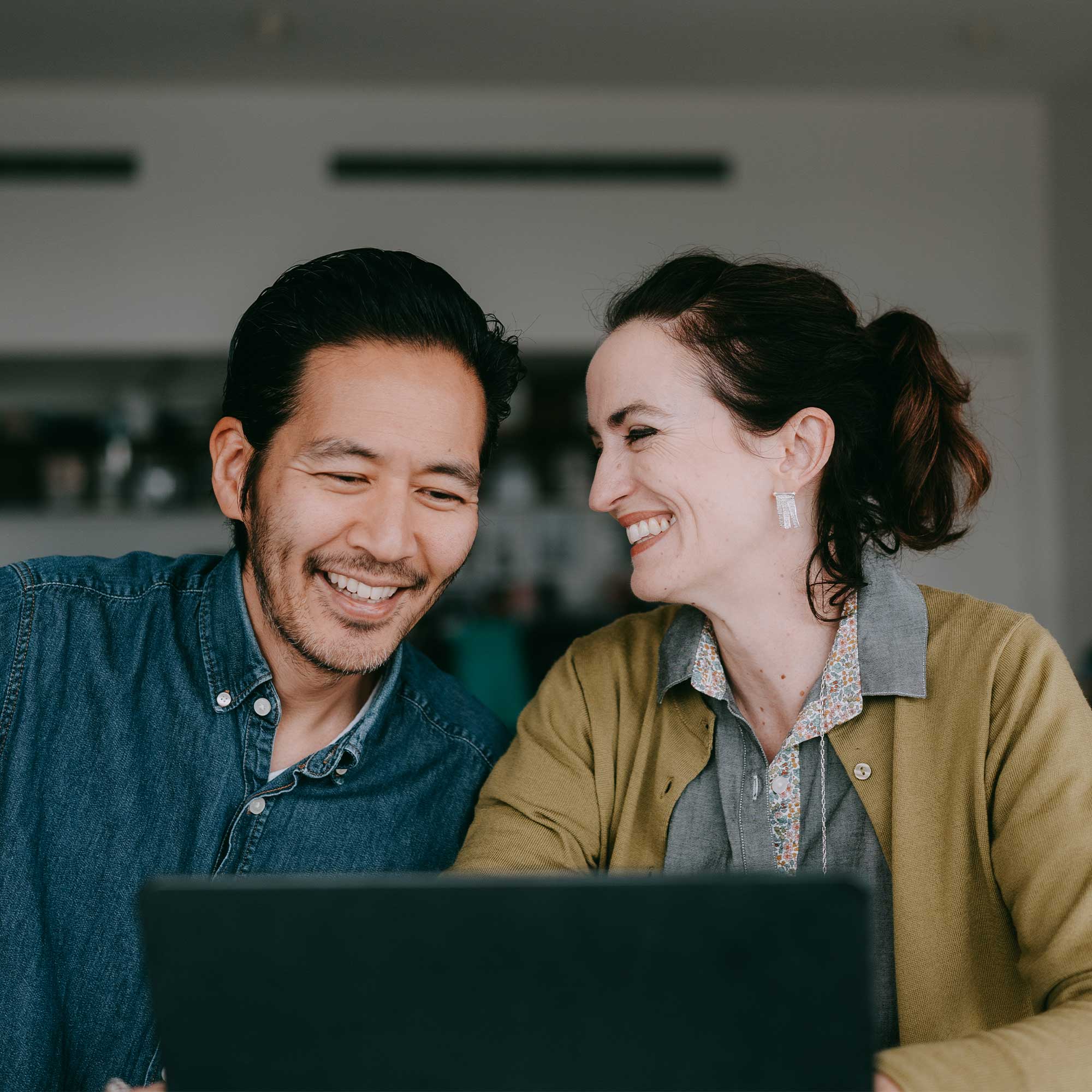 a man and woman looking at a laptop