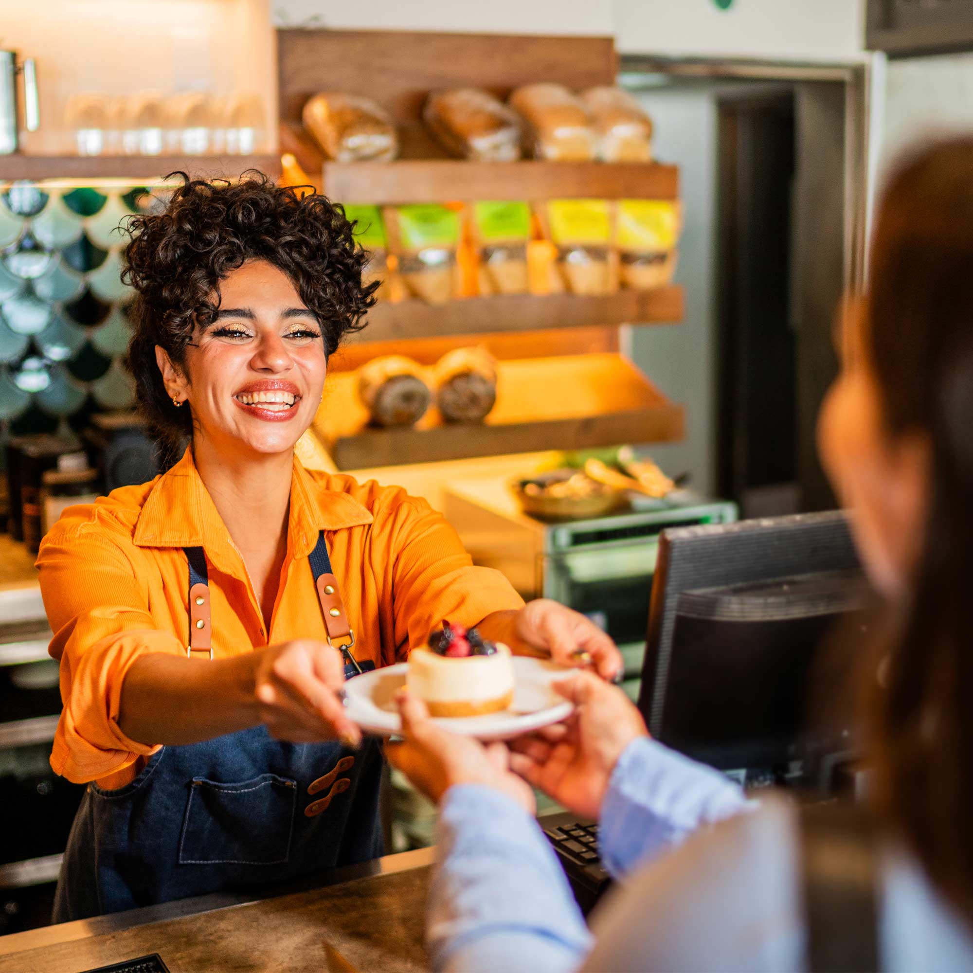 a woman handing a plate of dessert to a customer