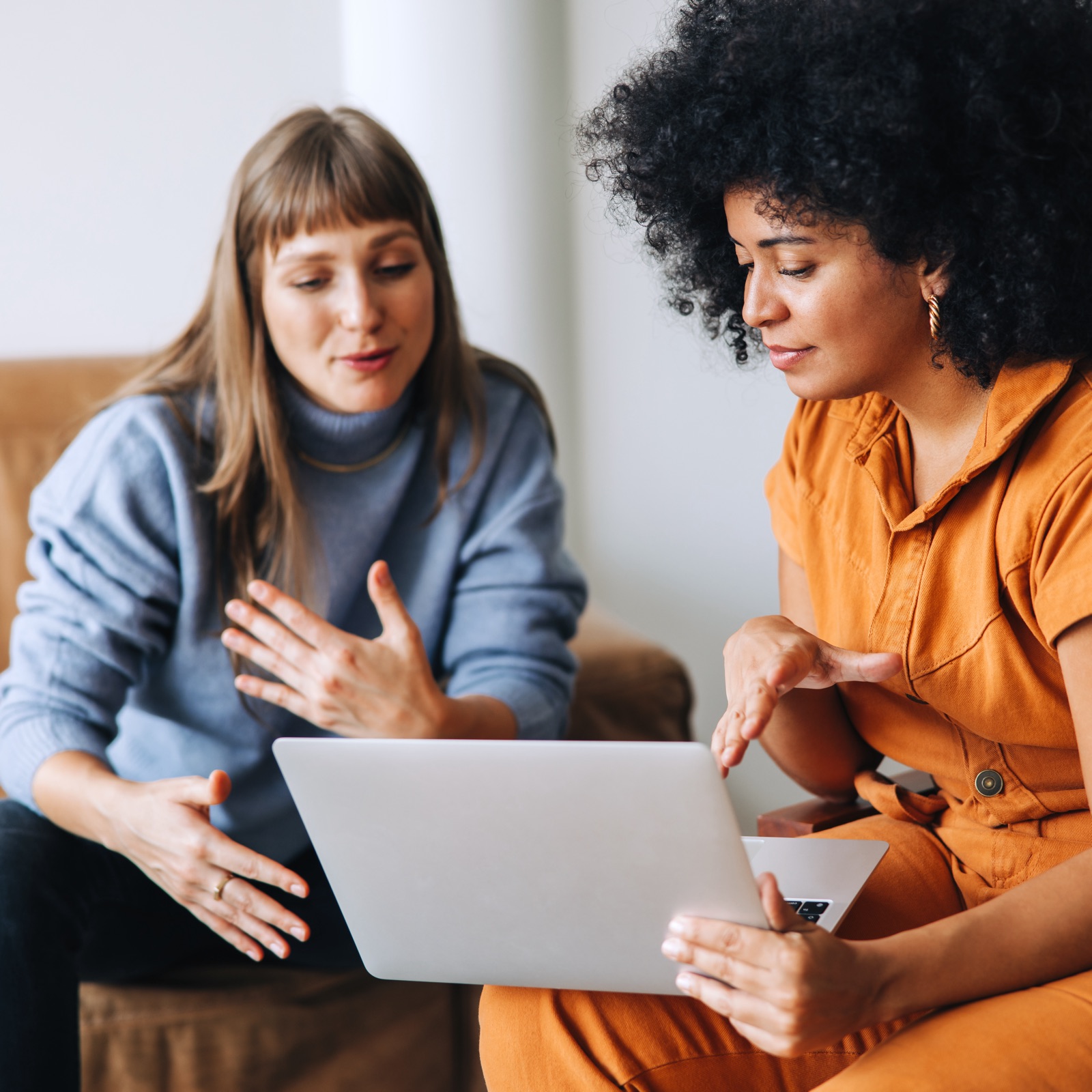 a woman looking at a laptop screen while another woman looks at her