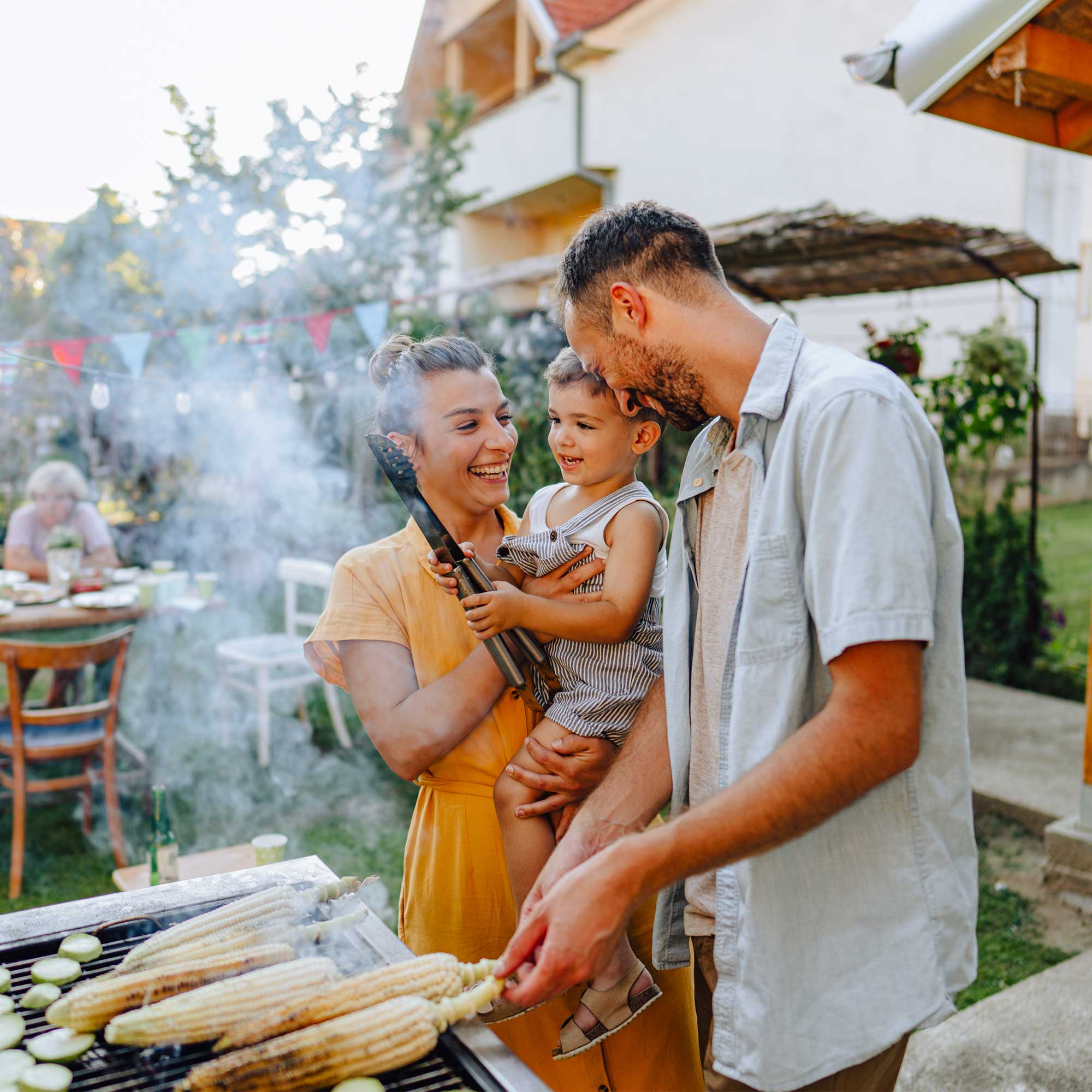 a group of people standing around a grill with corn on it