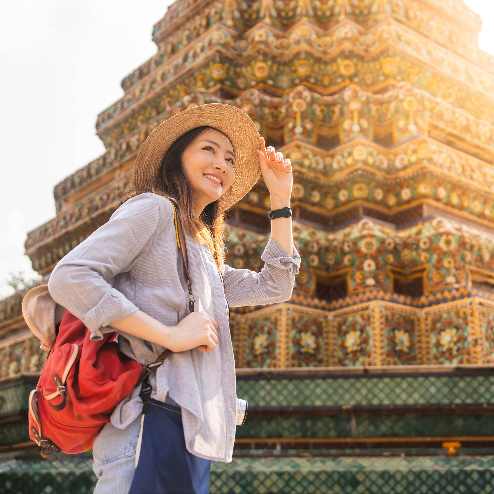 a woman wearing a straw hat and standing in front of a colorful building