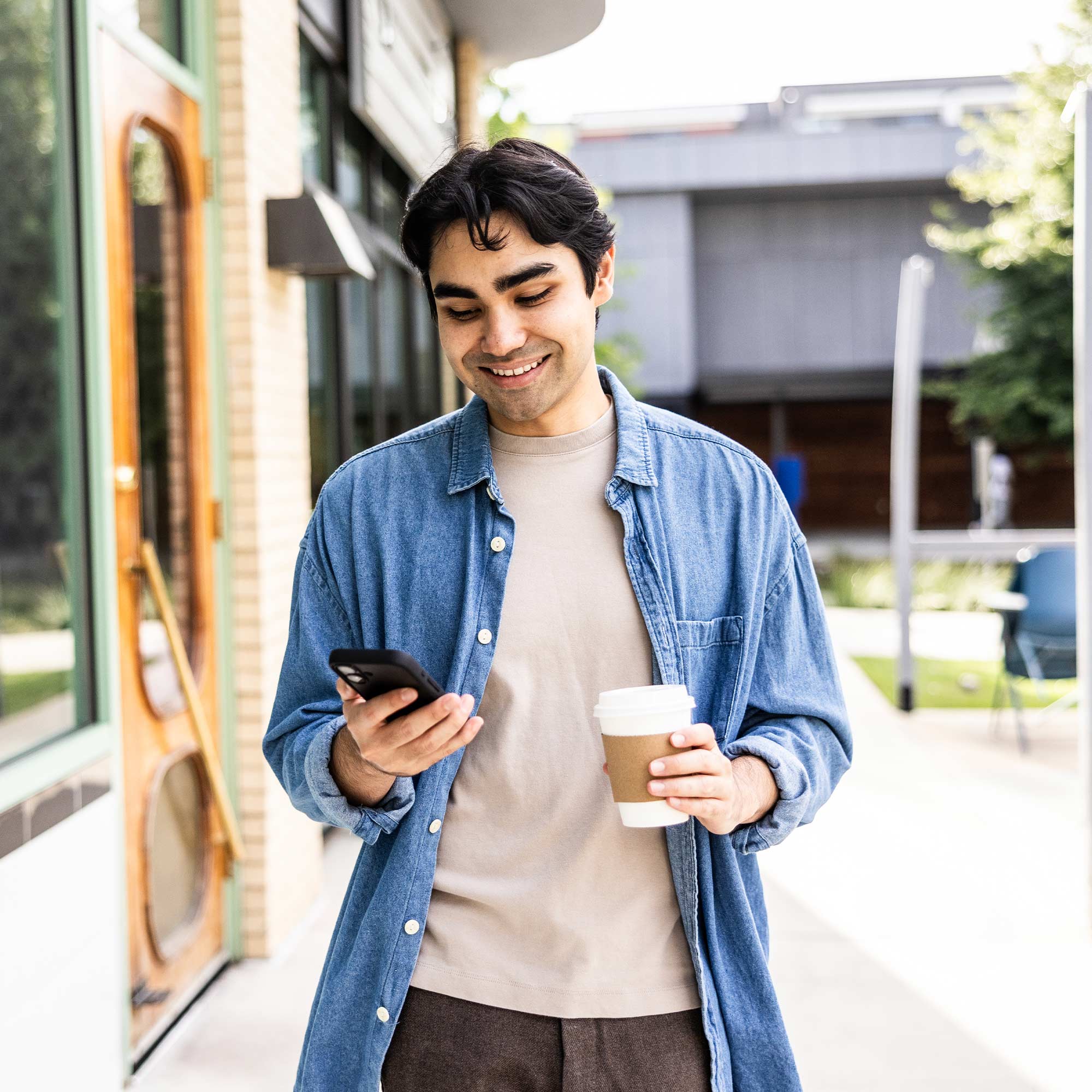 a man holding a coffee cup and a phone