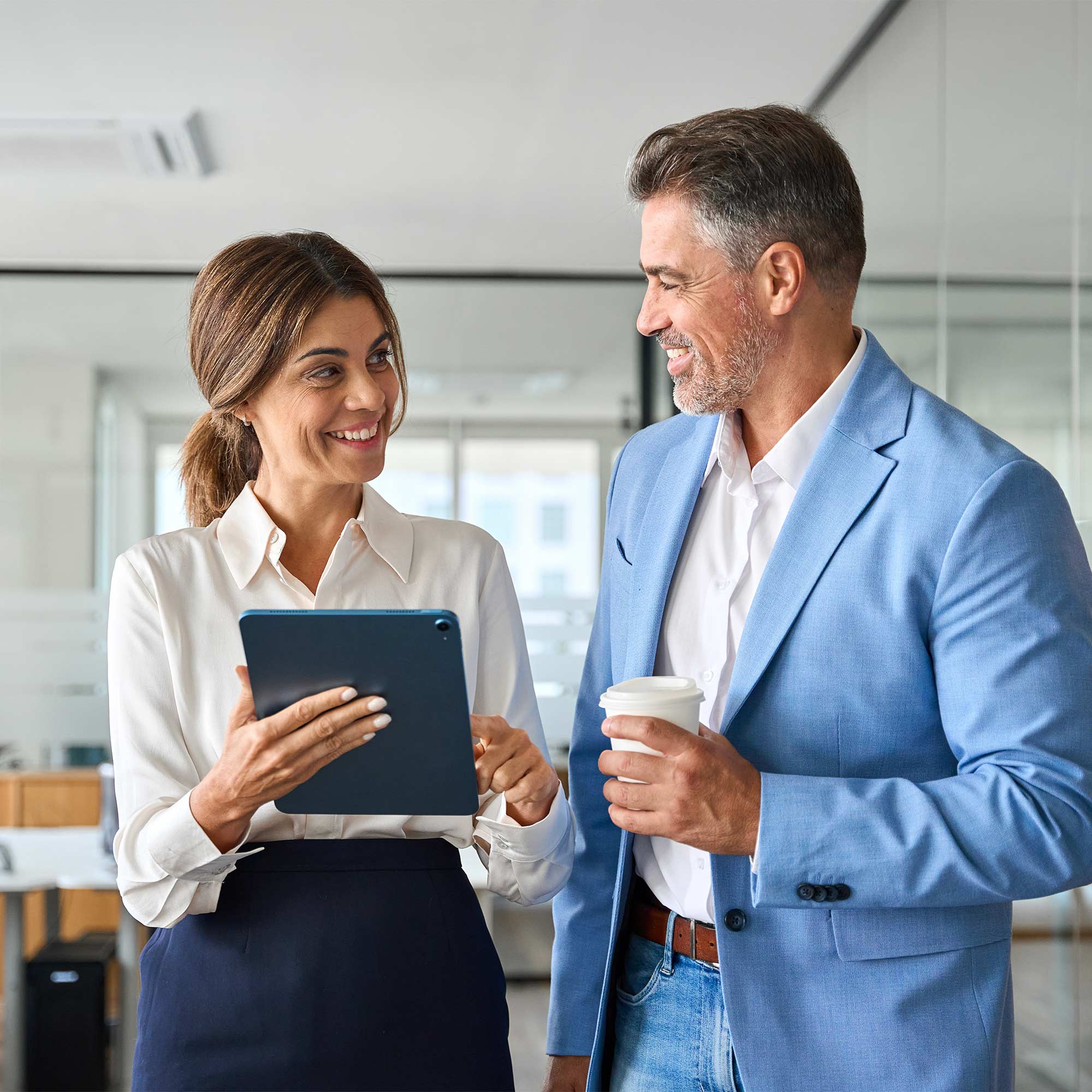 a man and woman holding a tablet and a cup of coffee