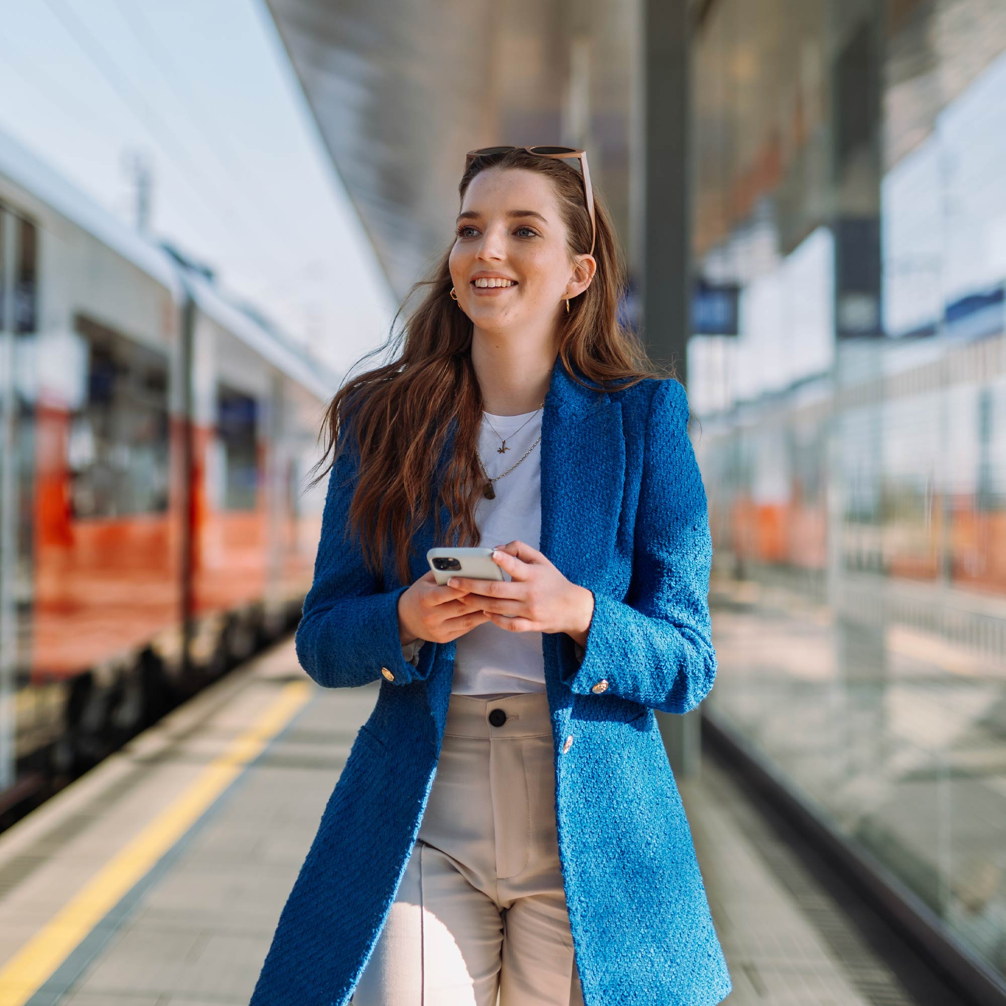 a woman standing in a train station holding a phone