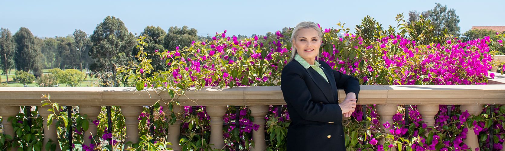 a woman standing next to a railing with purple flowers