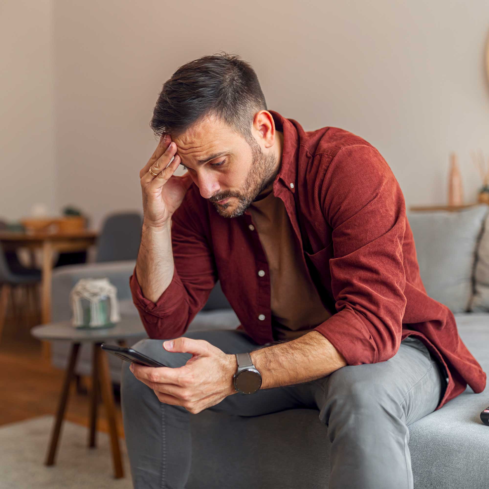 a man sitting on a couch looking at a phone