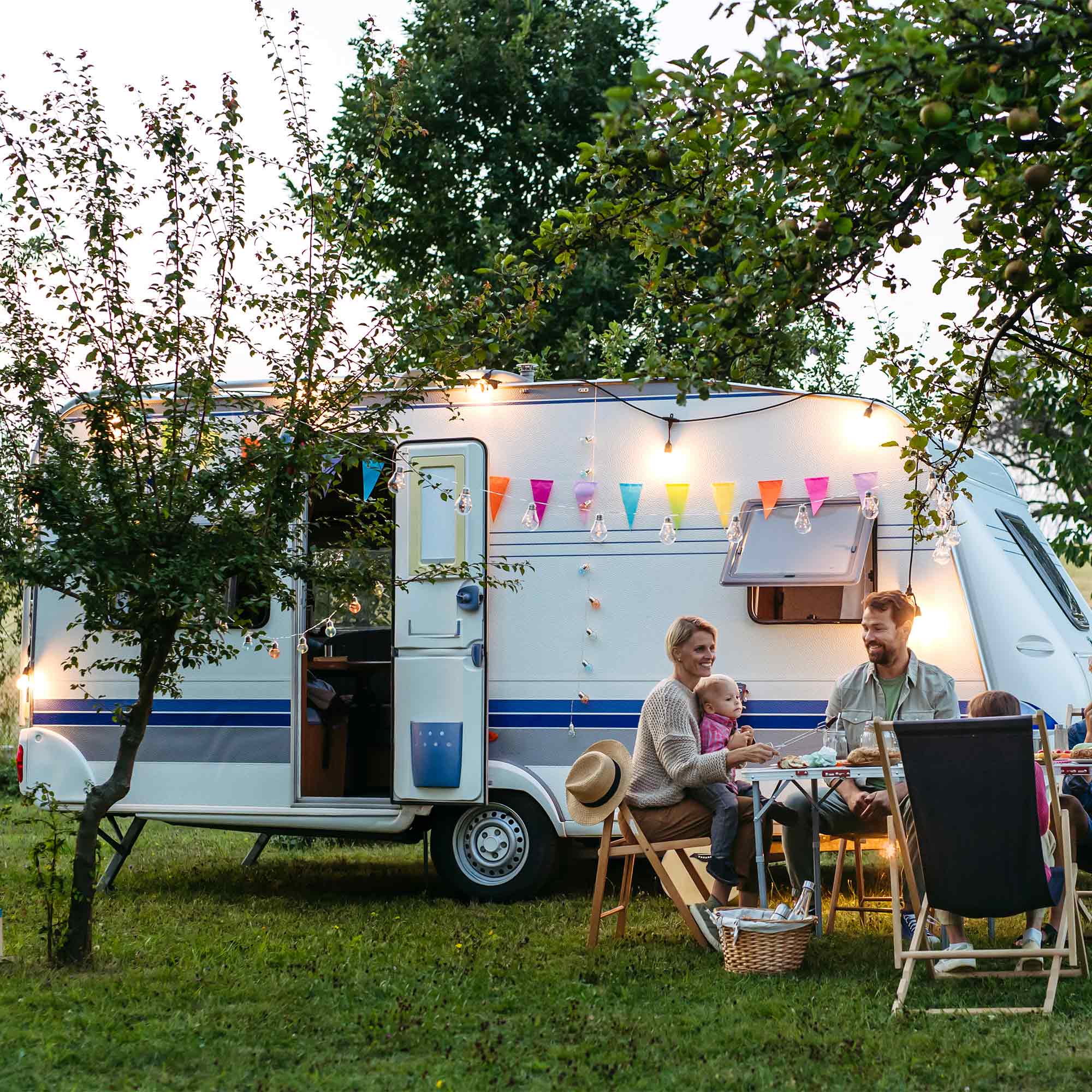 a family sitting at a table outside a camper