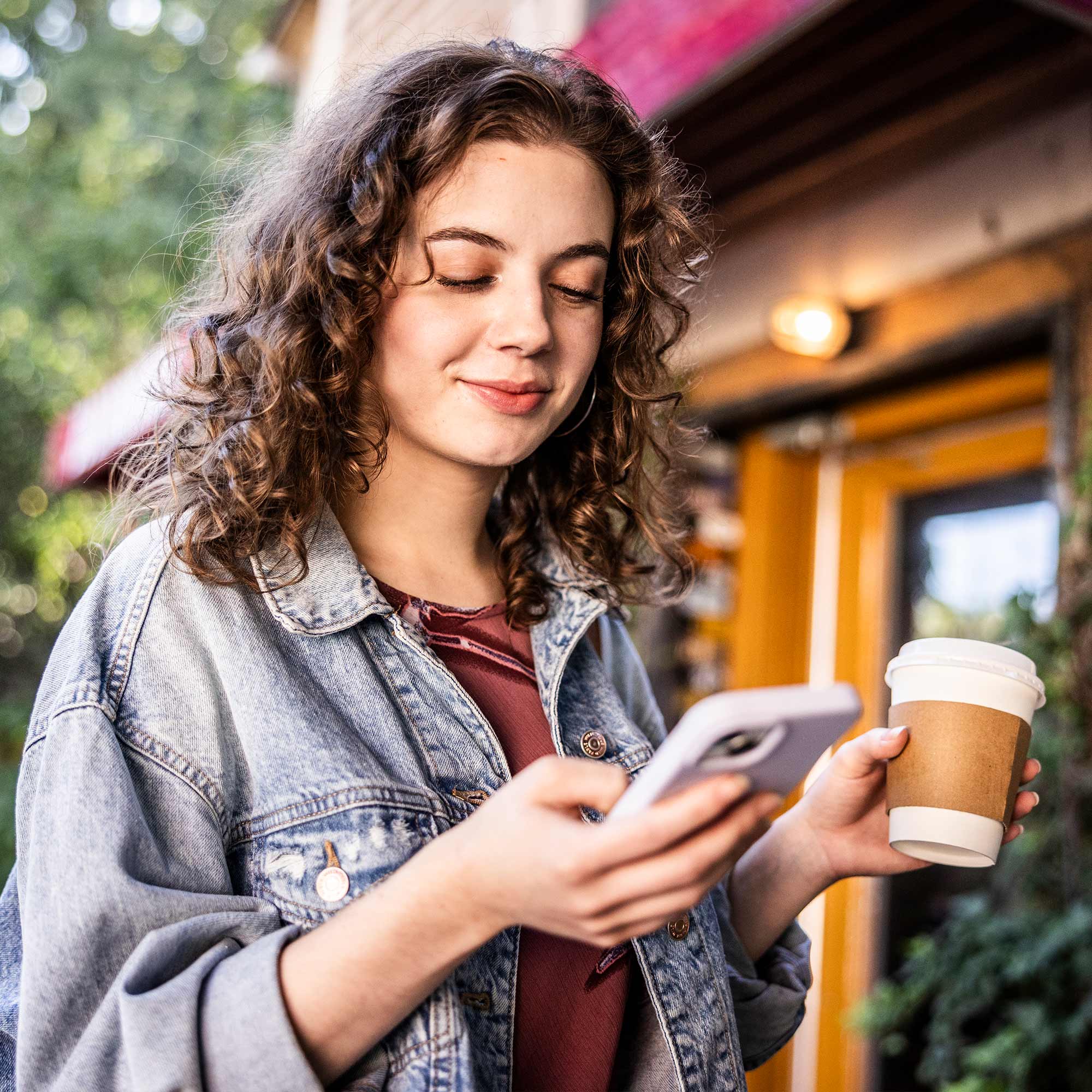 a woman holding a coffee cup and a phone