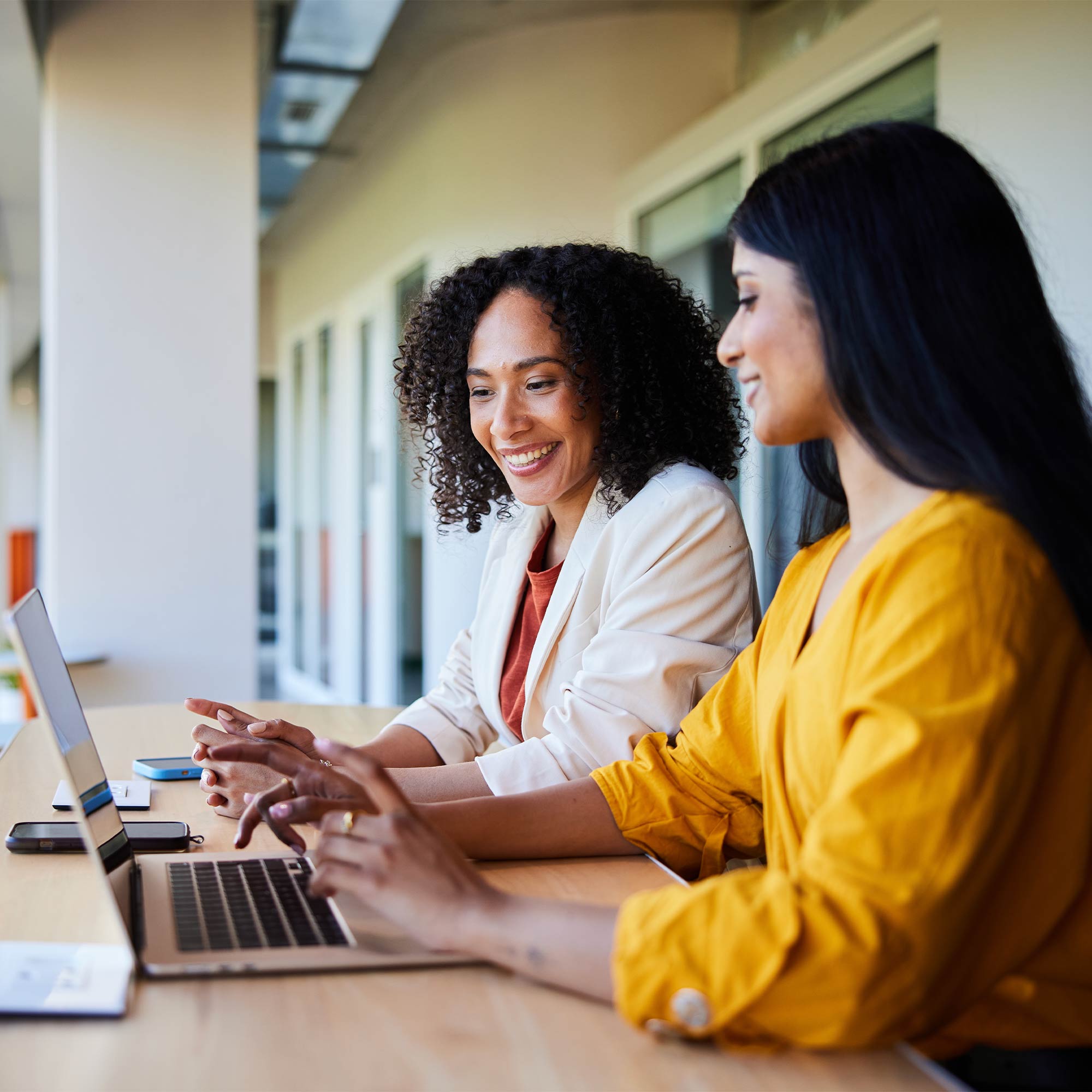a group of women sitting at a table looking at a laptop