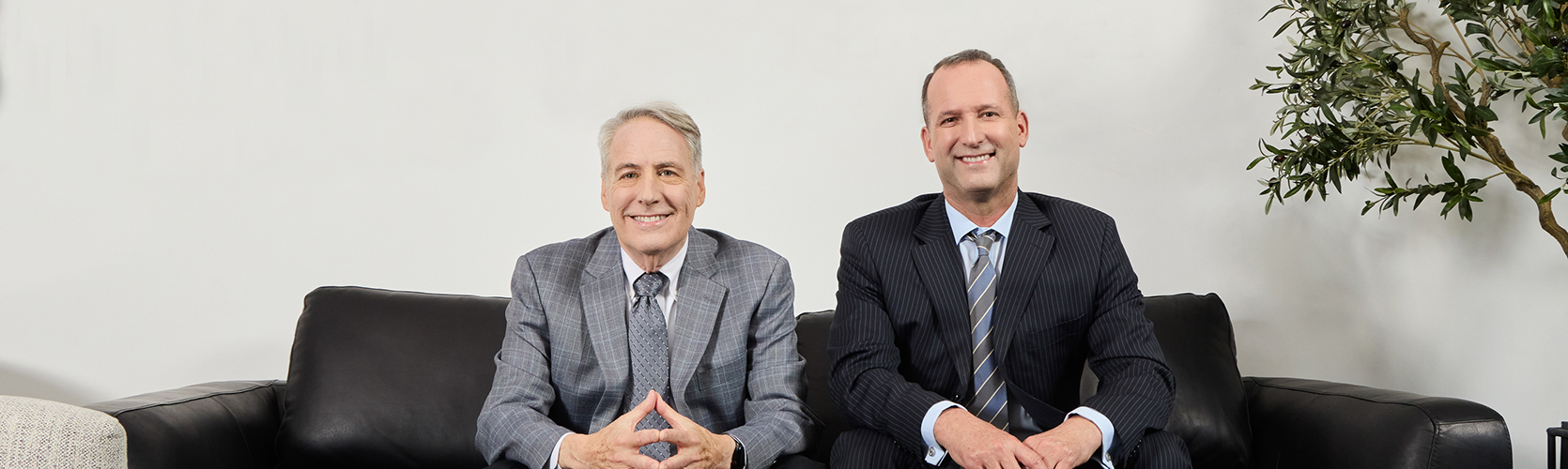 two men in suits sitting on a couch