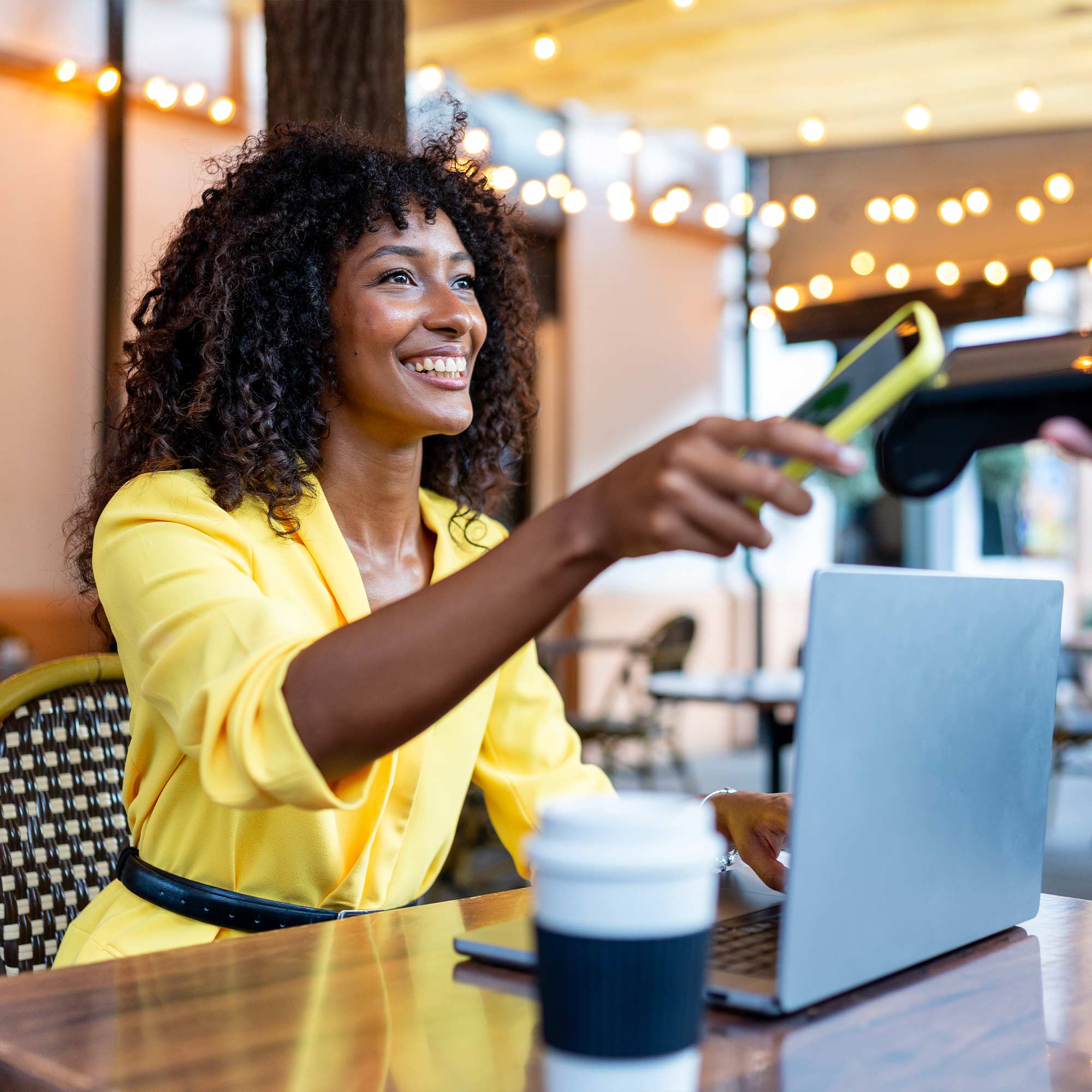a woman sitting at a table with a laptop and a credit card reader