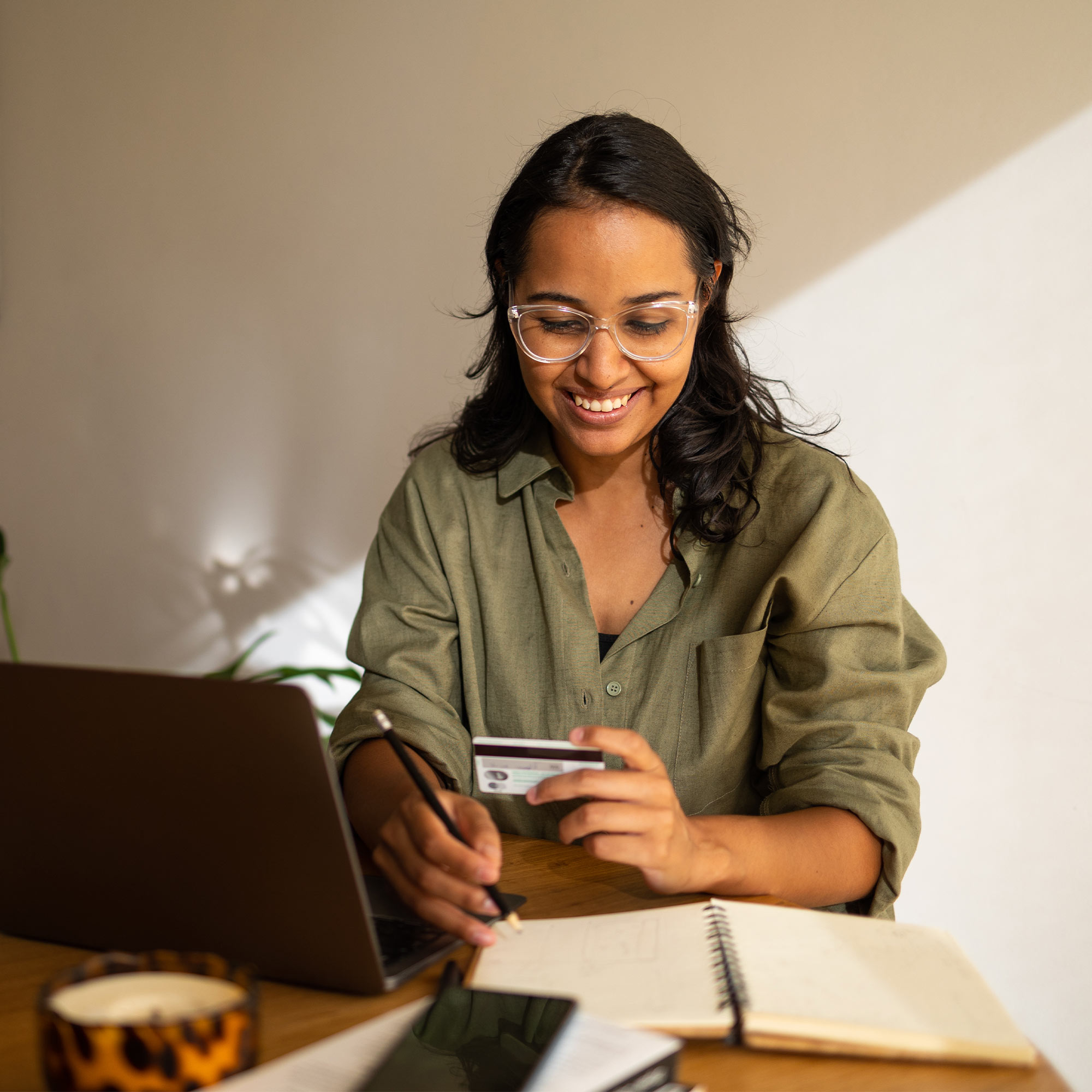 a woman holding a credit card and looking at a laptop
