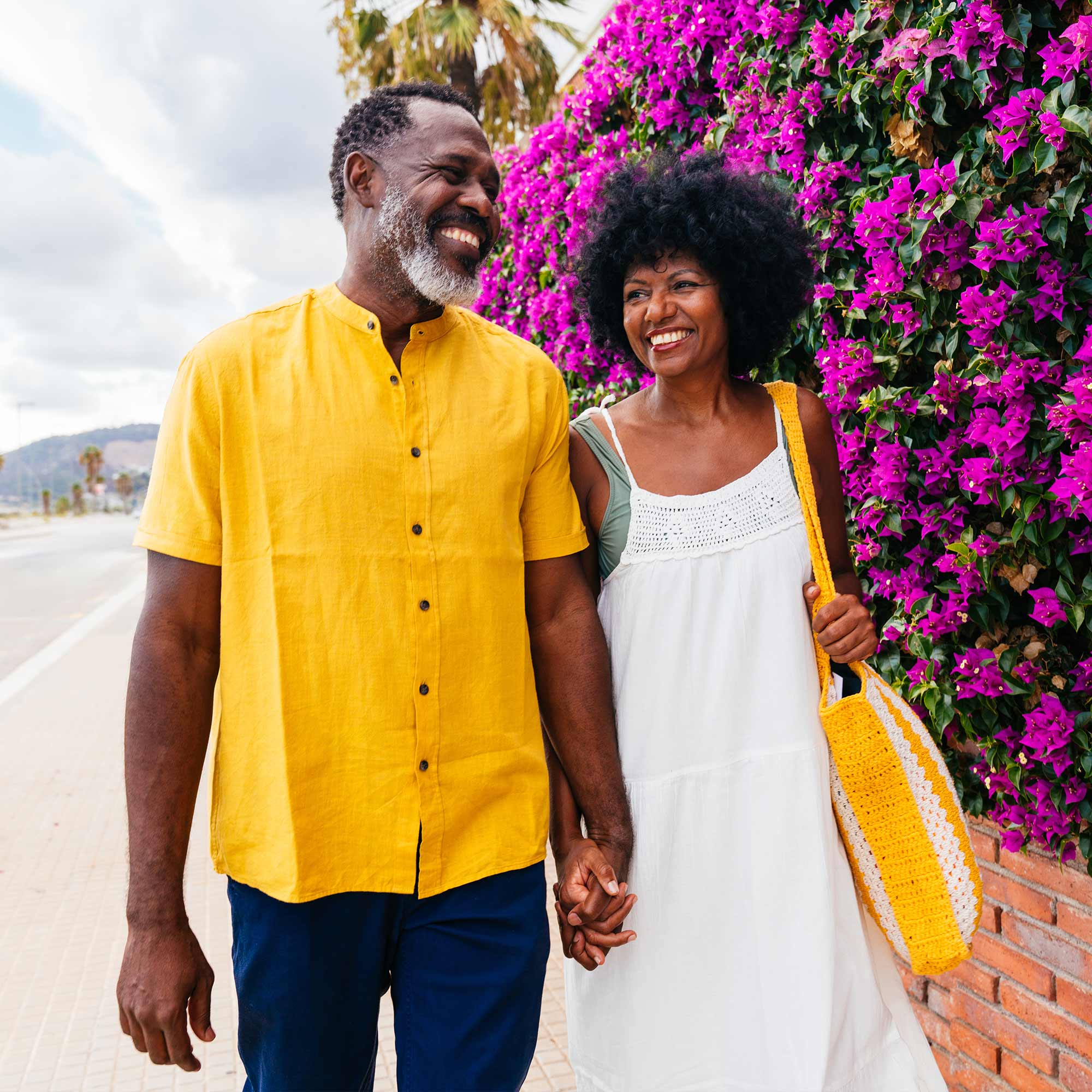 a man and woman holding hands and walking on a sidewalk