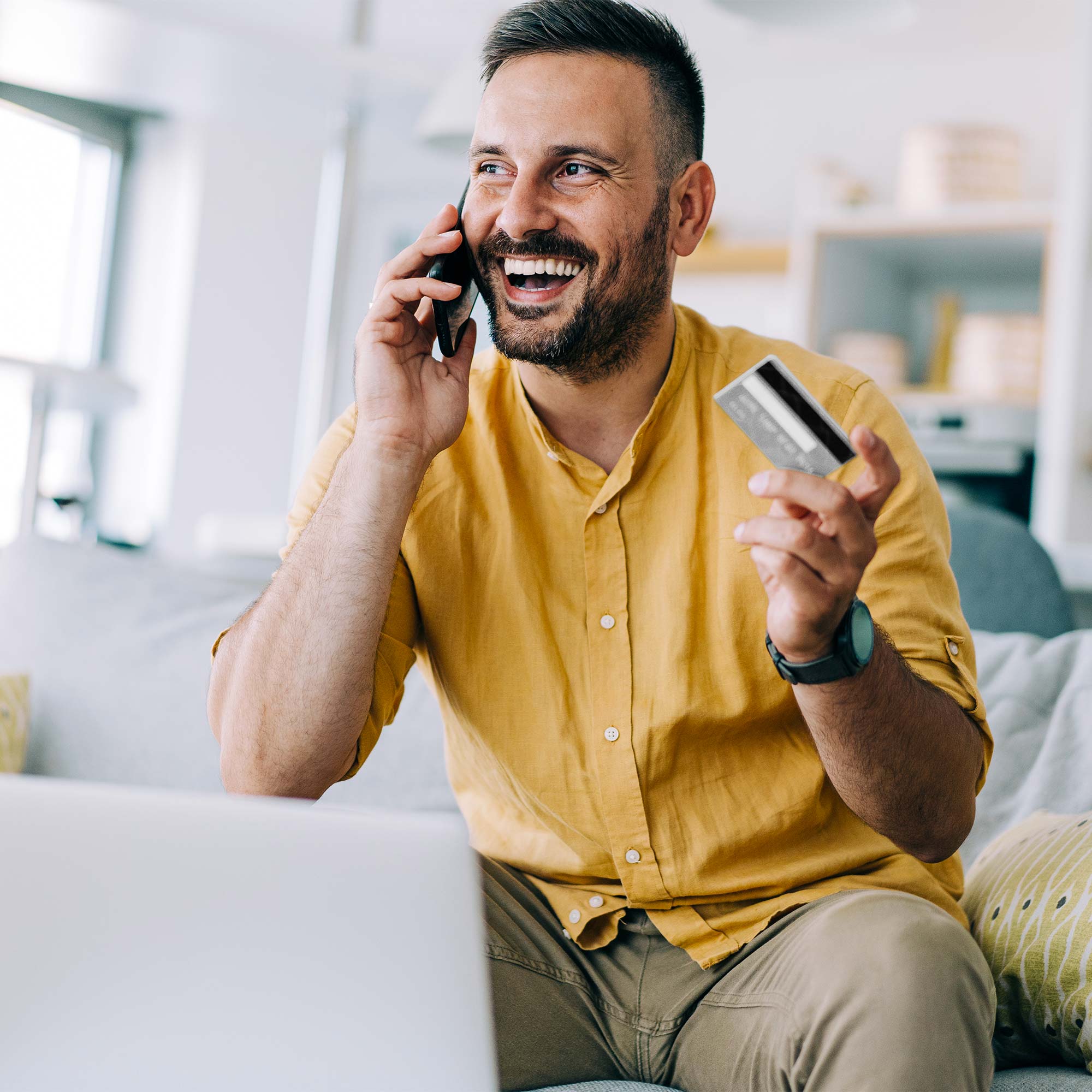 a man holding a credit card and talking on a phone