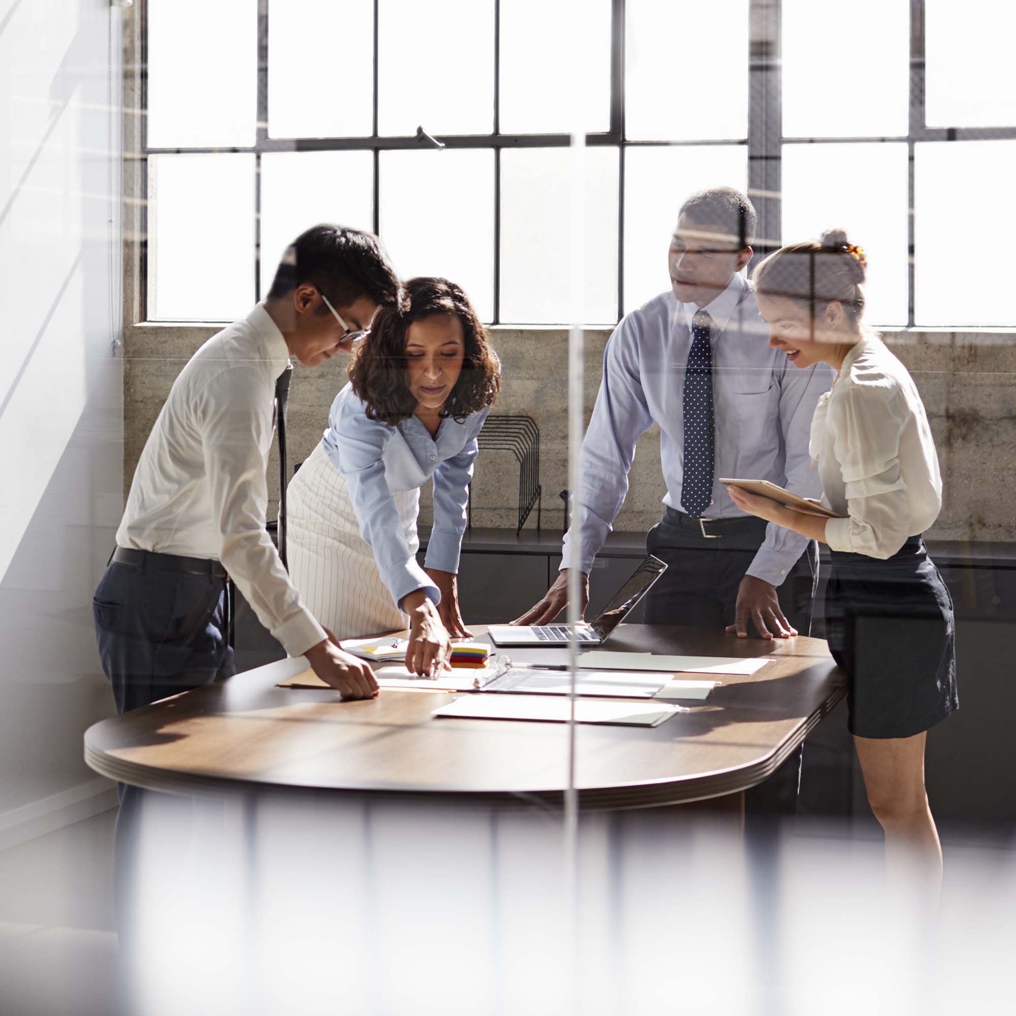 a group of people standing around a table looking at papers