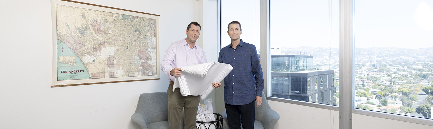 two men holding a rolled up white paper