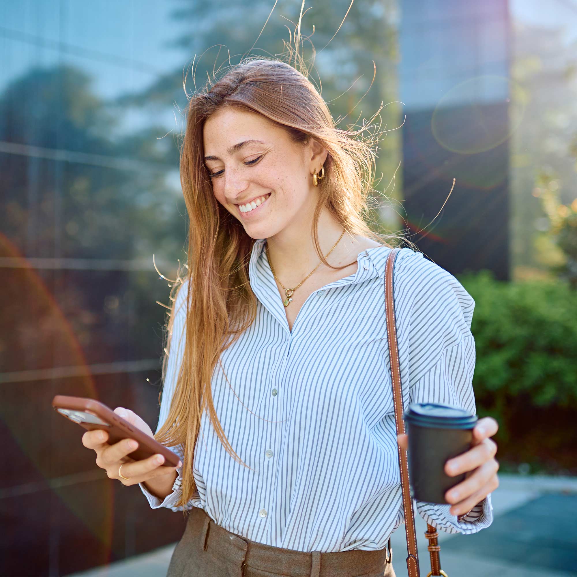 a woman holding a coffee cup and a cell phone
