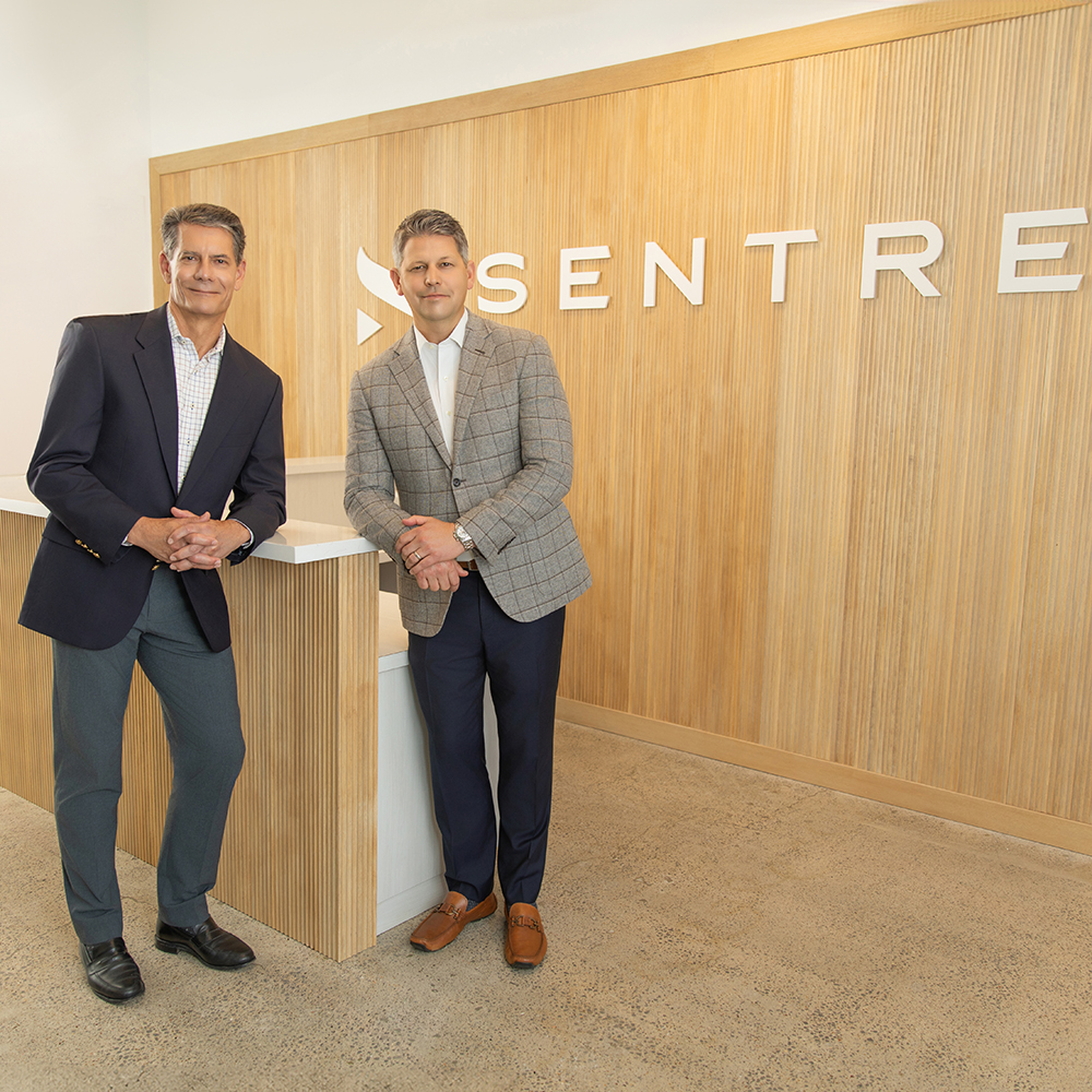 two men standing next to a desk