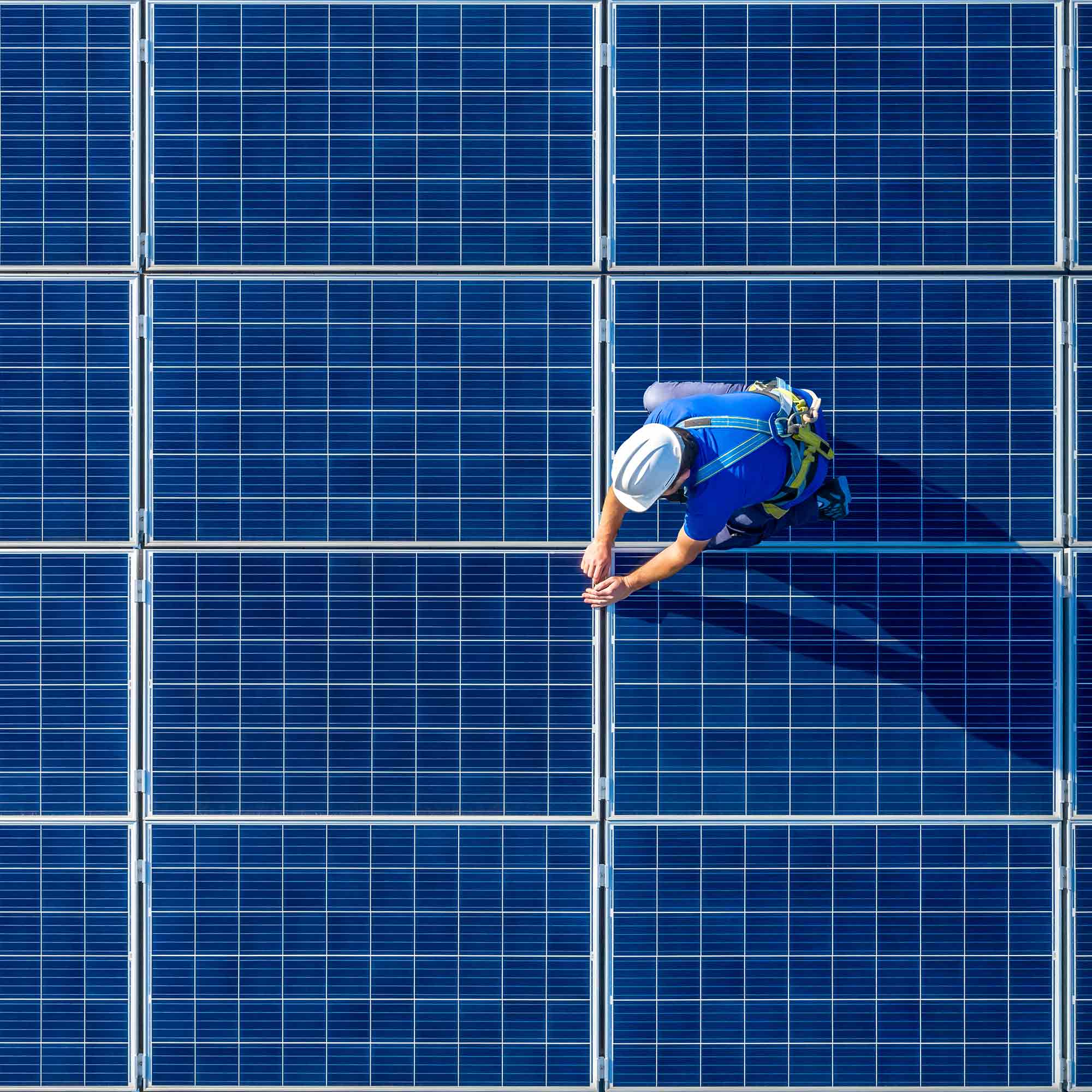 men in safety vests installing solar panels on a roof