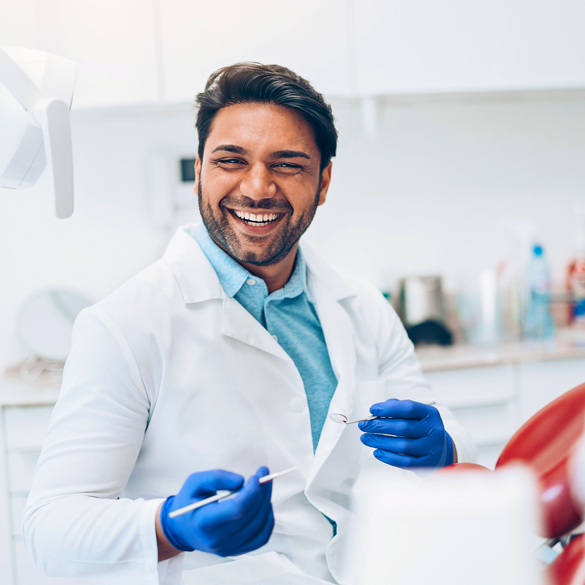 a man in a white coat and blue gloves holding a toothbrush
