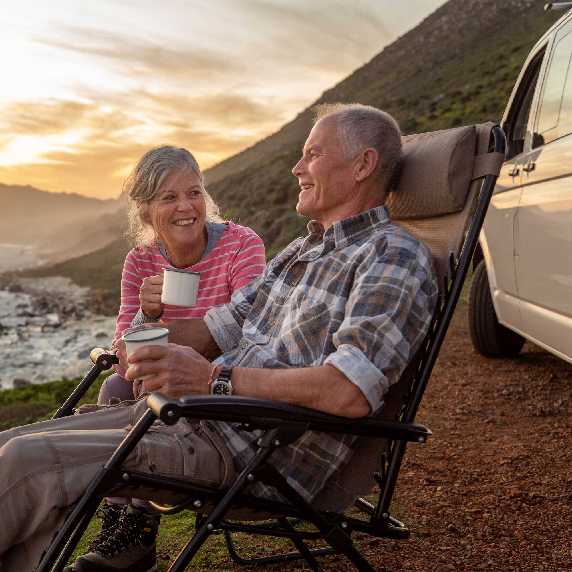 a man and woman sitting in chairs by a van